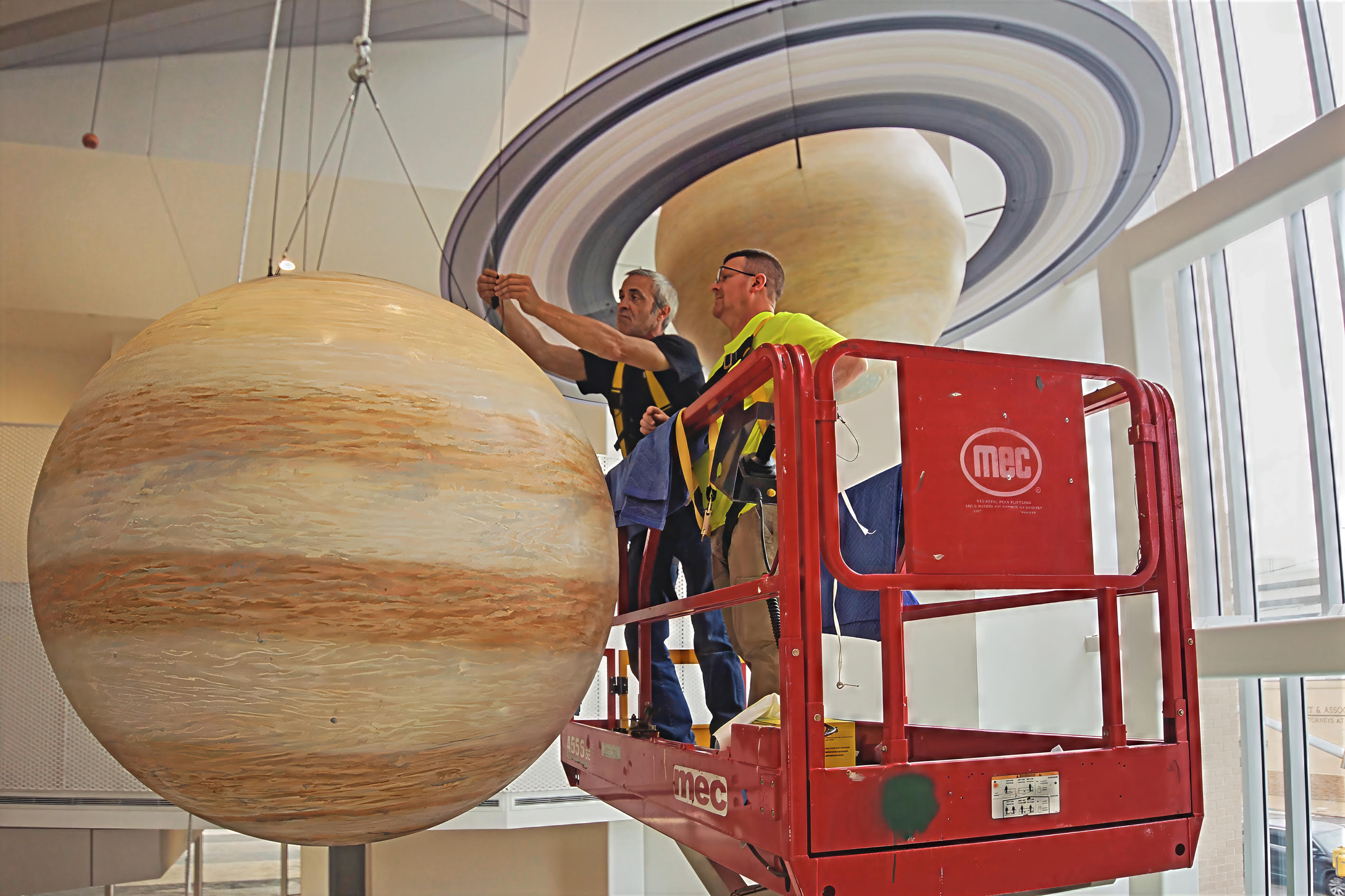 Installation crew hanging the Jupiter model beneath Saturn